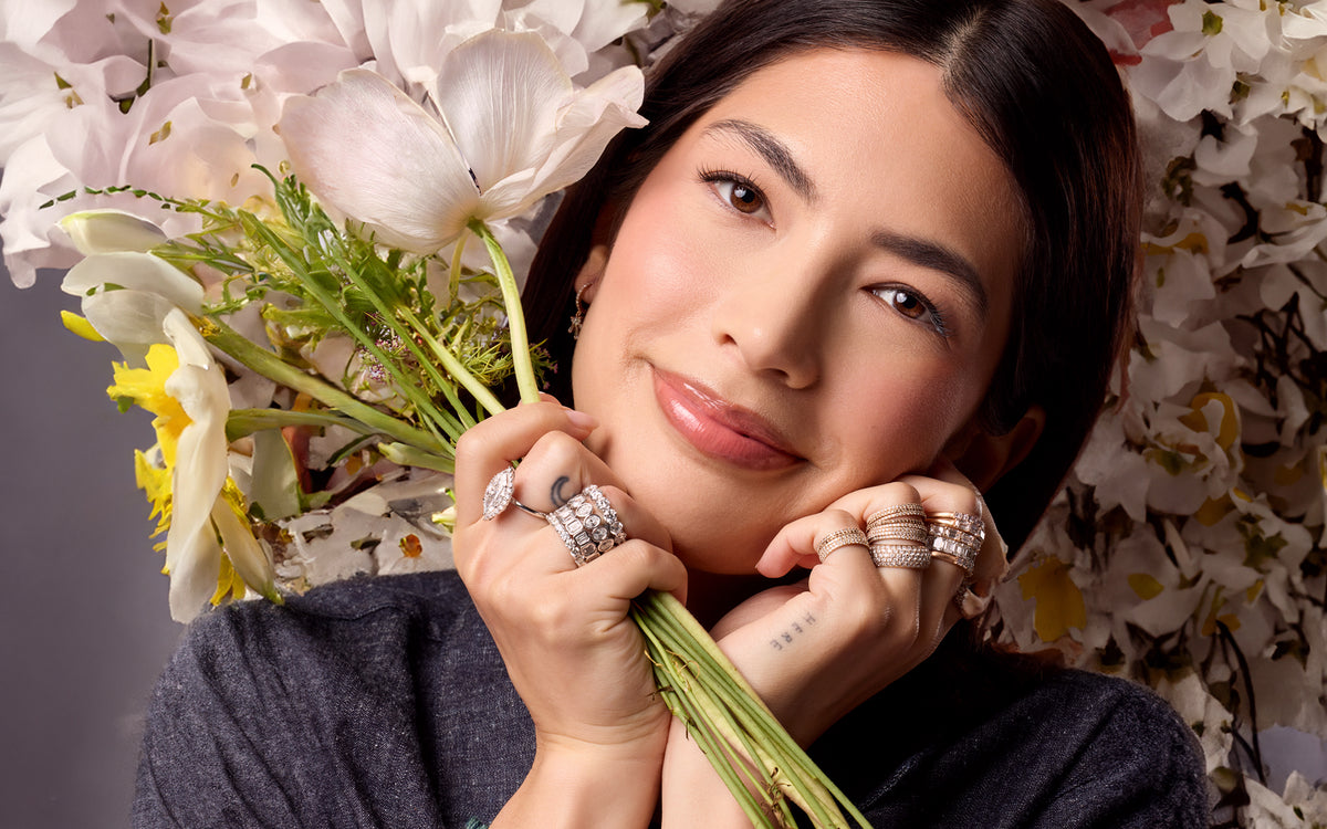 Dominique Cohen Shop the Look white gold diamond ultimate ring stacks on lovely young woman in front of white flowers; call 323-404-2959 for shop help